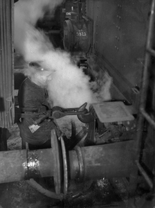 222812 Afbeelding van een rangeerder van de N.S. bij het koppelen van een stoomlocomotief aan een rijtuig.